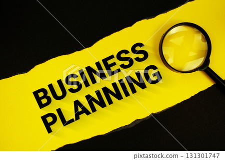 Business Planning text on yellow with black paper torn ripped and magnifying glass 131301747