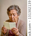 An elderly woman looking anxiously at her bankbook 131302139