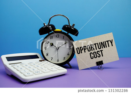 Opportunity Cost text with calculator and alarm clock on blue and purple background 131302286