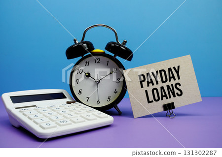Payday Loans text with calculator and alarm clock on blue and purple background Payday Loans text with calculator and alarm clock on blue and purple background 131302287