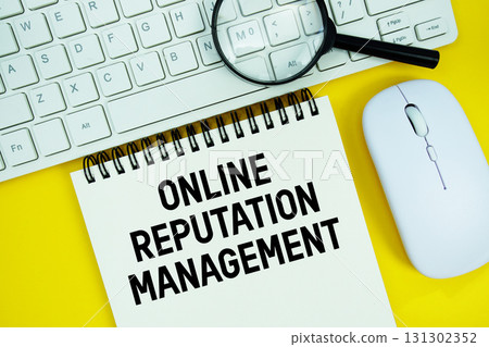 Notepad with the text "ORM Online Reputation Management" and white keyboard, wireless mouse, magnifying glass on yellow background 131302352