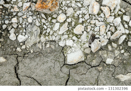 Close-up view of cracked dry ground with rocks and rough texture. 131302396