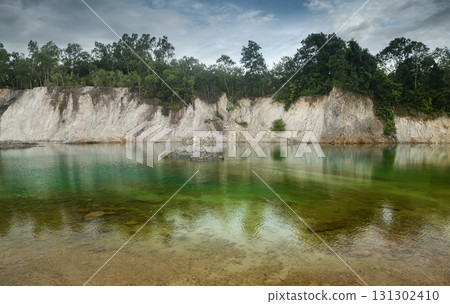 Scenic emerald pond with cliffs and reflection of trees. 131302410