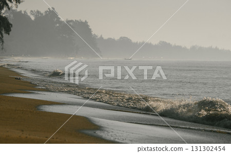 Misty ocean waves rolling onto sandy beach shore. 131302454