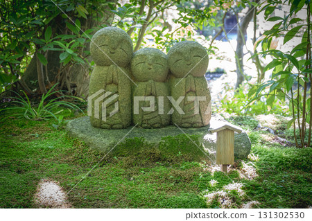 Stone statues of three monks in a peaceful Japanese garden setting 131302530