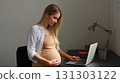 Happy pregnant mom working remotely on laptop. Online video call. Smiling and engaged, the pregnant mom showcases her multitasking skills during a video call. 131303122