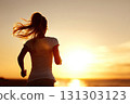 Silhouette of a young woman running on the beach during sunset. The vibrant hues of sunset create a magical atmosphere as the silhouette of a young woman runs along the shoreline. 131303123
