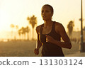 Portrait of a young woman running on the beach during sunset. A carefree spirit, the young woman runs on the beach, the sunset casting a warm glow on her joyful face. 131303124