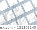 Natural light casts shadows from wildflowers on several sheets of white paper lying on a blue background. Mockup 131303145