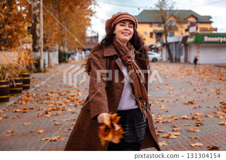 A beautiful woman enjoys her weekend stroll through the fall city, wearing classic fashion and savoring the fresh air, the silence, and her peaceful surroundings. 131304154