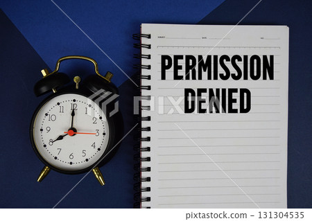 Permission Denied text written on notepad with alarm clock on blue background Permission Denied text written on notepad with alarm clock on blue background 131304535
