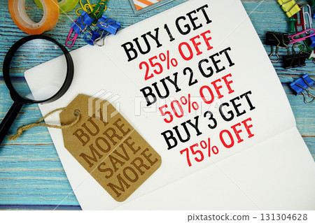 Buy 1 get 25%, Buy 2 get 50%, Buy 3 get 75% text on a notepad paper and Buy More Save More with price tag surrounded by office supplies and magnifying glass on a blue wooden surface Buy 1 get 25%, Buy 2 get 50%, Buy 3 get 75% text on a notepad paper and Buy More Save More with price tag surrounded by office supplies and magnifying glass on a blue wooden surface 131304628