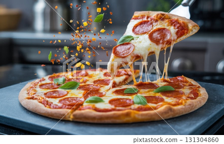 Hot pepperoni pizza slice lifted with melted cheese strings and falling spices 131304860