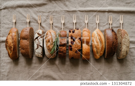 Assortment of artisanal bread slices and loaves with wooden forks on linen fabric 131304872