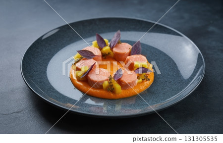 Meticulously plated gourmet salmon dish with vibrant orange puree and fresh purple basil 131305535