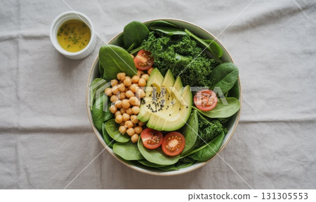 Vibrant vegan power salad bowl with fresh greens, avocado, chickpeas, and dressing 131305553