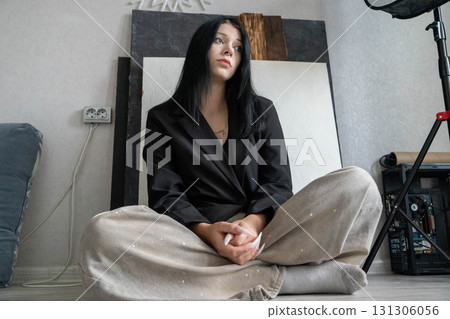 Young woman sitting cross-legged brainstorming a new project Young woman sitting cross-legged brainstorming a new project 131306056
