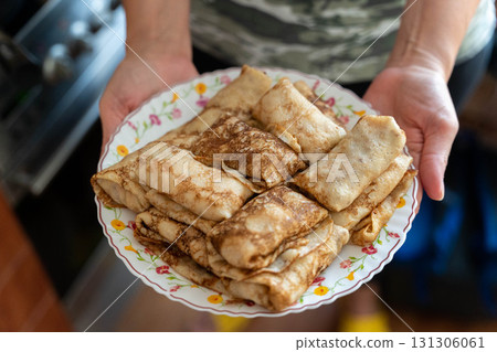 Hands holding plate of cooked pancakes blini crepes 131306061
