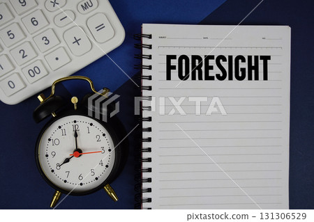 Foresight text written on notepad with calculator and alarm clock on navy blue background Foresight text written on notepad with calculator and alarm clock on navy blue background 131306529