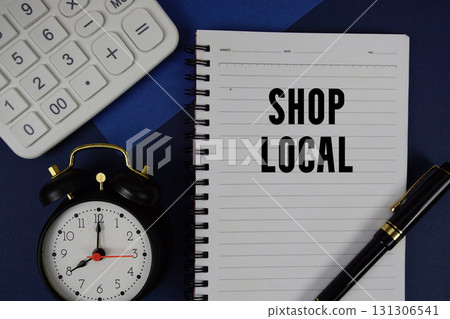 Shop Local text written on notepad with calculator and alarm clock on navy blue background 131306541