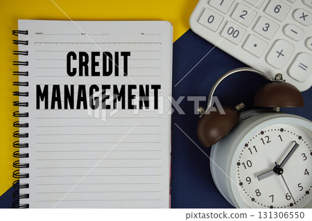 Credit Management text written on notepad with calculator and alarm clock on navy blue background 131306550