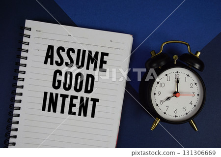 Assume Good Intent text written on notepad with alarm clock on navy blue background Assume Good Intent text written on notepad with alarm clock on navy blue background 131306669