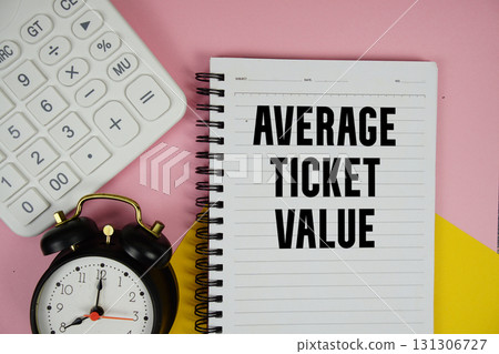 Average Ticket Value text written on notepad with calculator and alarm clock on pink background 131306727