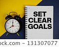 Set Clear Goals text written on notepad with alarm clock on yellow background 131307077