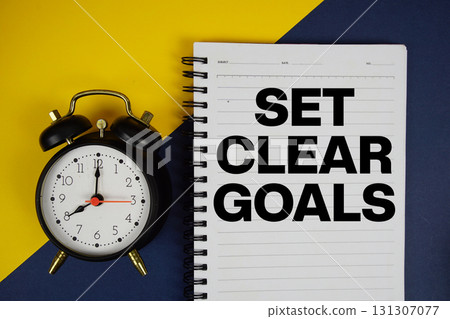 Set Clear Goals text written on notepad with alarm clock on yellow background 131307077