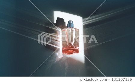 Pink perfume bottle on the light background in the rays of sun with highlights. Pink perfume bottle on the light background in the rays of sun with highlights. 131307139