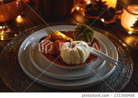 Autumnal table setting with decorative pumpkins, candles and string lights. 131308486