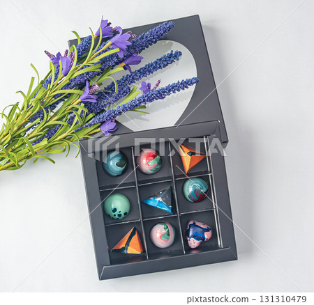 Tempered chocolate candies with glossy painted body in a box with blur elements. View from above 131310479