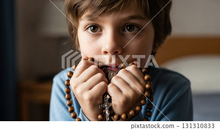 Boy stares ahead, hands close to his face. 131310833