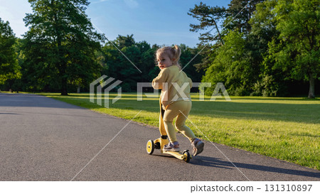 Child scooter riding. Girl yellow scooter park. Motion day lifestyle travel. Child scooter riding. Girl yellow scooter park. Motion day lifestyle travel. 131310897