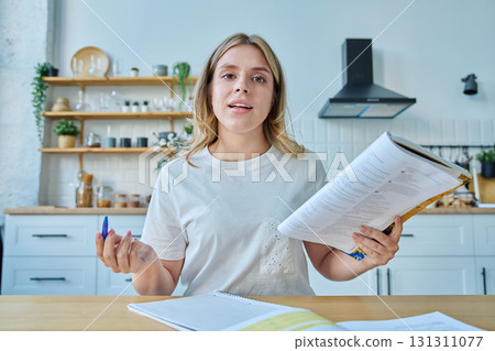 Webcam portrait female university student, sitting at home at the table with textbooks Webcam portrait female university student, sitting at home at the table with textbooks 131311077