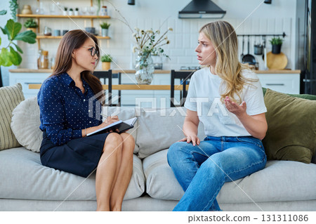 Female social worker working at home with young woman Female social worker working at home with young woman 131311086