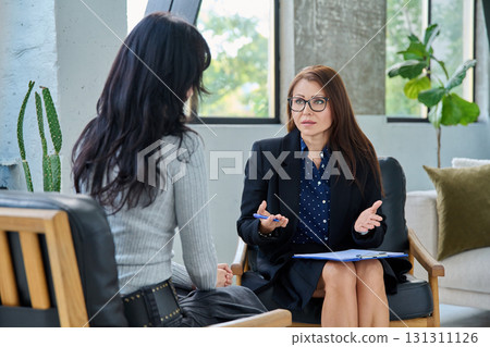Middle aged professional female psychologist, counselor working with young woman Middle aged professional female psychologist, counselor working with young woman 131311126