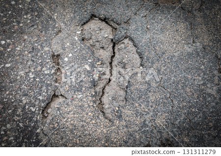 Severely cracked asphalt surface showing road damage and pavement erosion 131311279