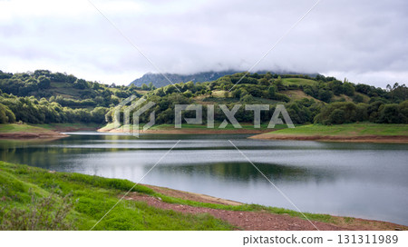 Scenic mountain lake with green hills and cloudy sky Scenic mountain lake with green hills and cloudy sky 131311989