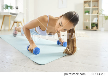 Woman Doing Pushups With Dumbbells In Plank Position During Home Workout Woman Doing Pushups With Dumbbells In Plank Position During Home Workout 131313348