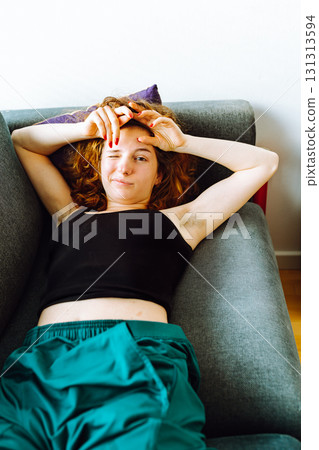 young red-haired woman tired lies on sofa 131313594