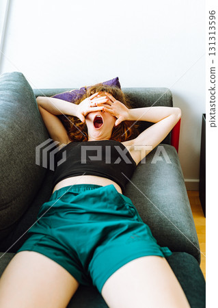 young red-haired woman tired lies on sofa 131313596
