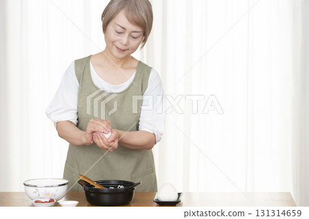 Senior woman making rice balls in the kitchen Senior woman making rice balls in the kitchen 131314659