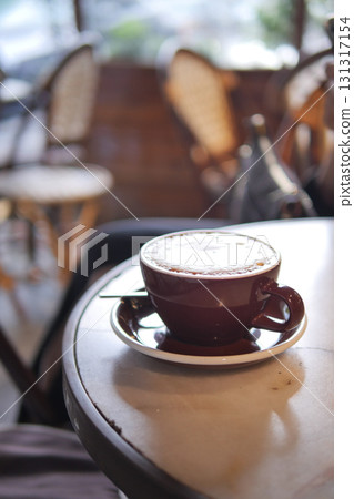 Warm coffee cup resting on a table in a cozy cafe Warm coffee cup resting on a table in a cozy cafe 131317154