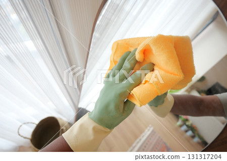 Cleaning a mirror in a bright indoor space with gloves 131317204