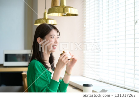 Woman eating a sandwich at a cafe Woman eating a sandwich at a cafe 131317262