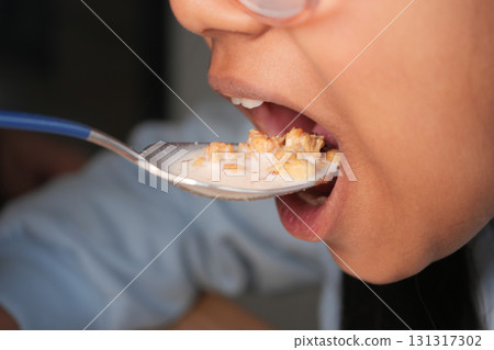 Child enjoys cereal with milk during breakfast time Child enjoys cereal with milk during breakfast time 131317302
