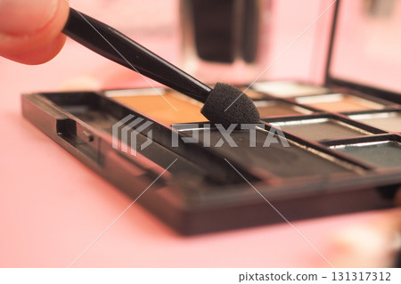 Applying makeup with a sponge applicator on a palette 131317312