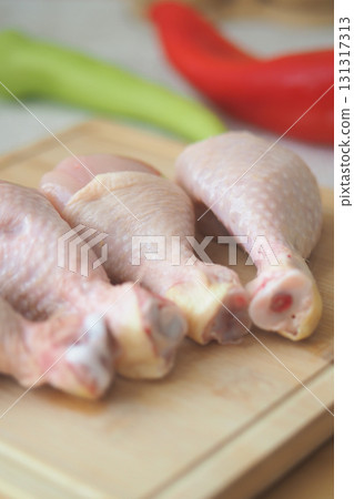 Fresh chicken drumsticks ready for cooking on a wooden board Fresh chicken drumsticks ready for cooking on a wooden board 131317313