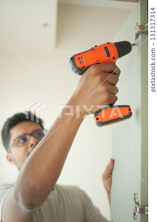 Man using a power drill to install cabinet hardware 131317314
